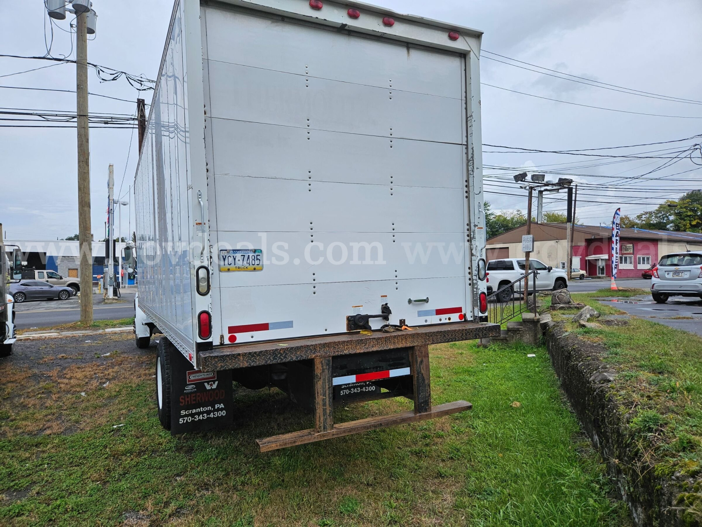Rear view of a box truck with a large white cargo trailer, showing back doors, red taillights, bumper, and wheel well; stock number 32136-61 visible on the trailer side.