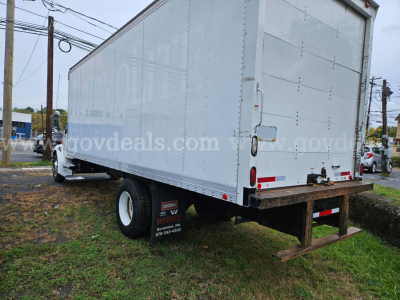 Box truck trailer shows rear and side views; white cargo box with reflective tape, undercarriage with single rear wheel, bumper, and hitch; visible-stock and dealership watermark across side.
