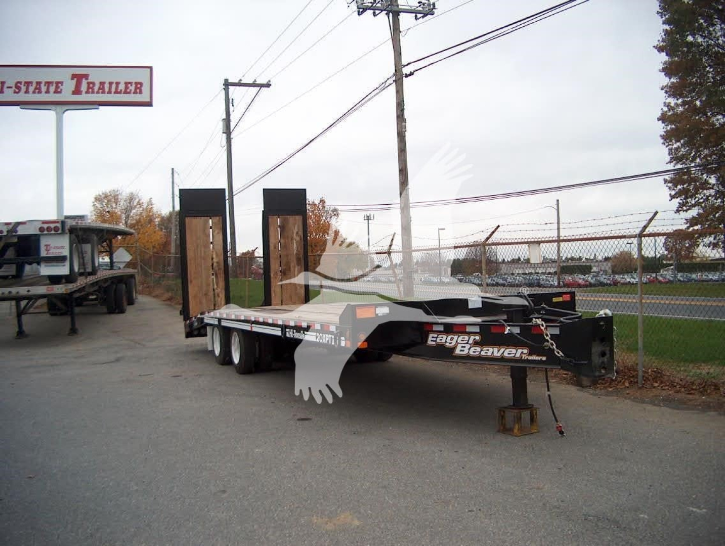 Eager Beaver 20XPT trailer in a lot showing flatbed deck and dual ramps with 'Eager Beaver' branding on side.