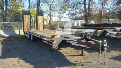 Trailer showing dual tandem axle with wooden decking and Eager Beaver branding on frame, ramp legs, and tongue. Visible text: Eager Beaver on frame.