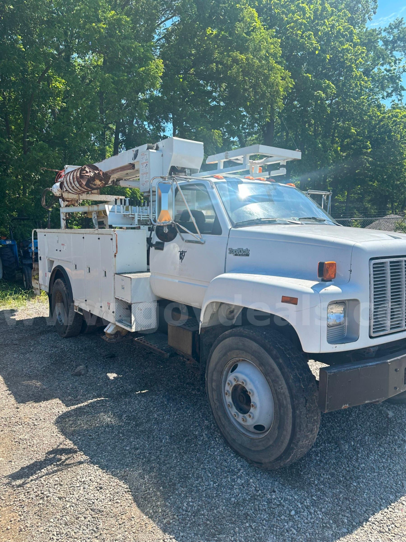 Truck chassis showing boom lift utility service body with electrical controls and hydraulic lines.