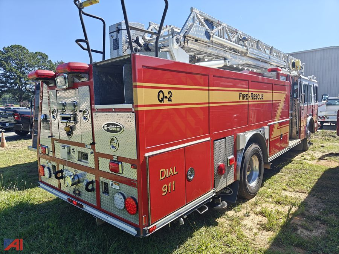 Fire truck rear and side view showing Q-2 Fire-Rescue logo, Dial 911, and equipment compartments on a red E-One Typhoon cab over engine.