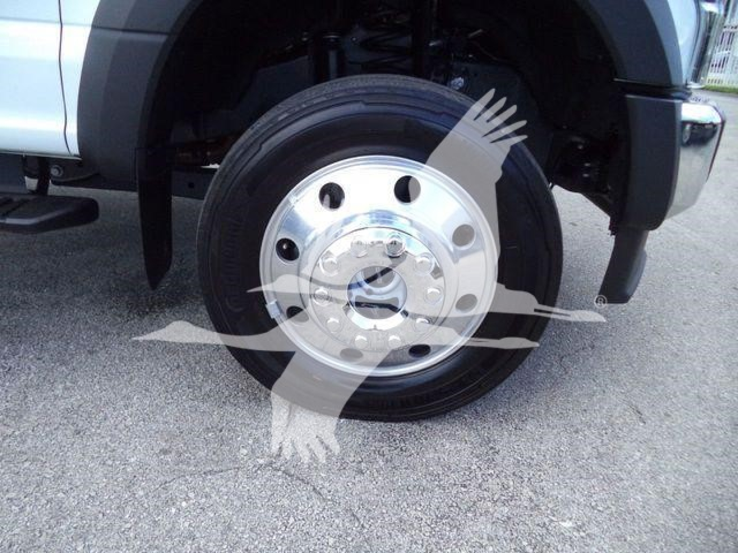 Wheel and front fender of a 2022 Ford F550 rolloff truck showing front wheel with steel rim and hub, partial bumper and tire tread.