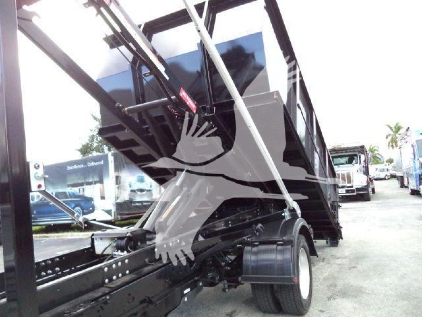 Ford F-550 roll-off truck front view showing hydraulic dump bed and folded hoist arms.