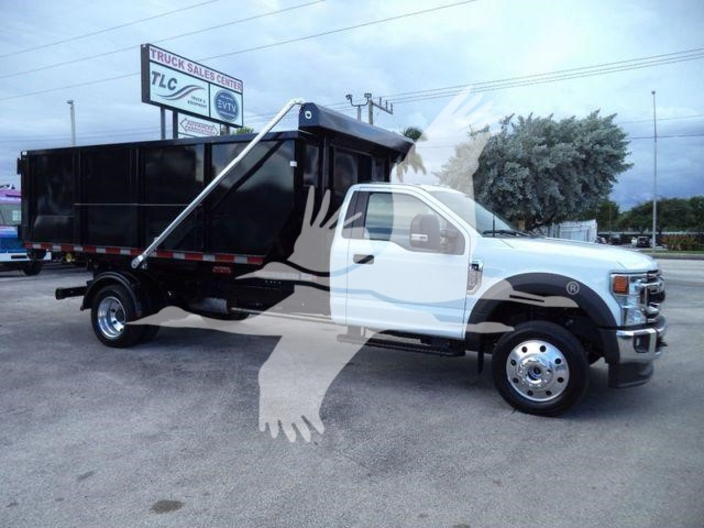 Ford F-550 roll-off truck with dump bed visible; no legible labels or serial numbers on the truck body in view.
