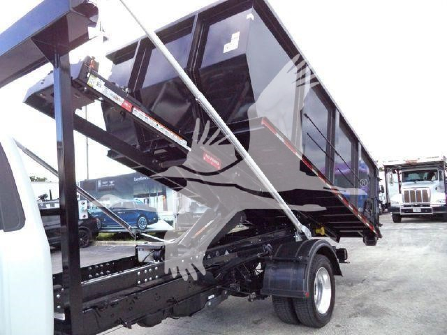 Ford F-550 roll-off truck in profile view showing dump bed and hydraulic supports.