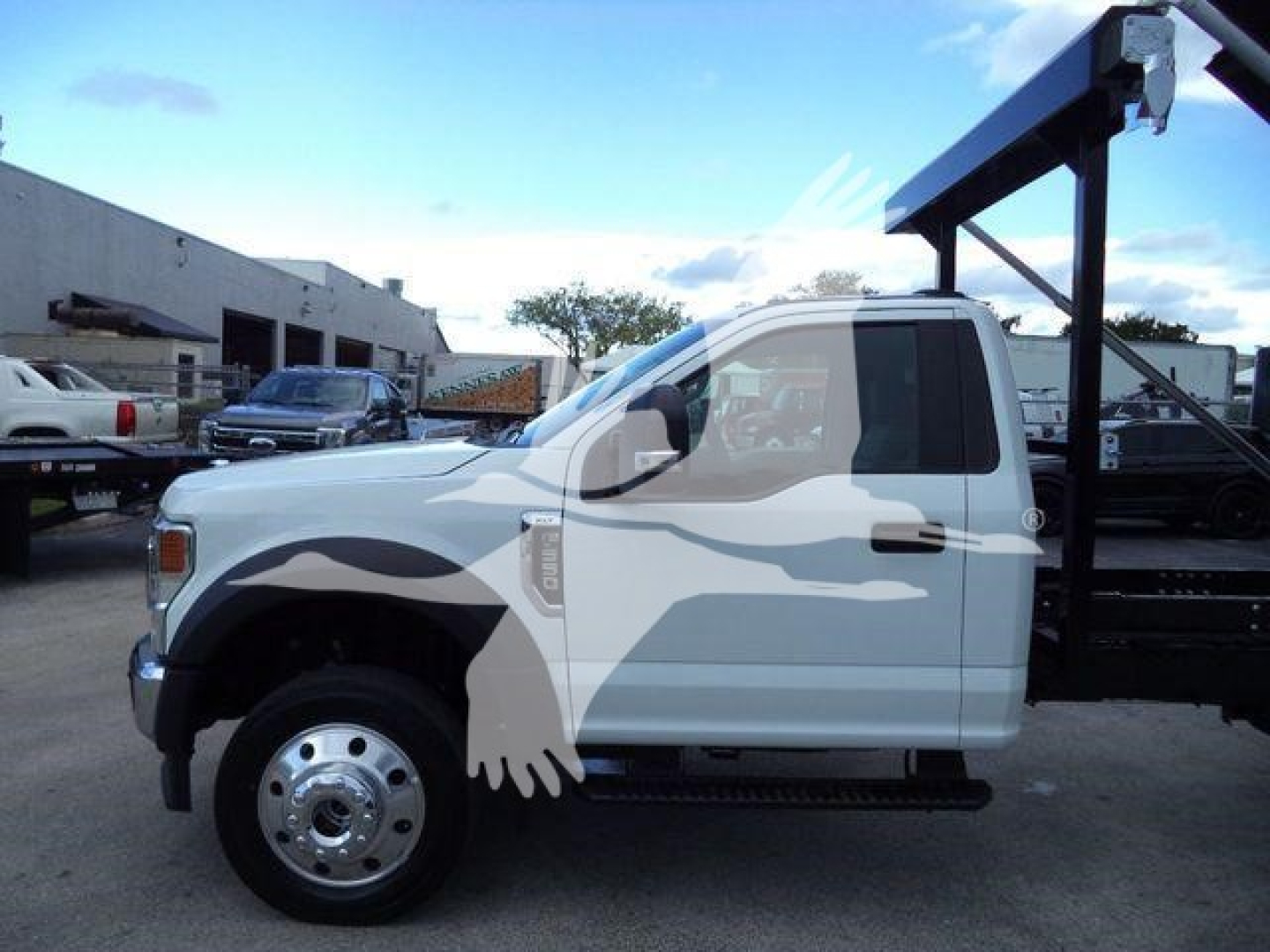 Ford F-550 cab with a rolloff body in side profile view showing standard wheel, cab door, and truck body against a yard setting.
