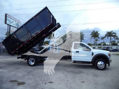 2022 Ford F550 dump truck in a rollover position showing a raised black dump bed and white cab.