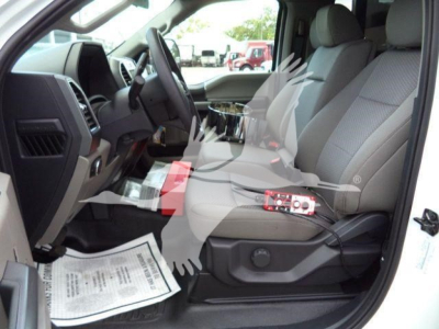 Ford F-550 cab interior showing front seats and dashboard with wiring/diagnostic tool on seat, driver-side door open.