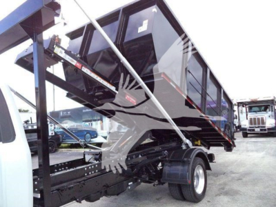 Ford F-550 roll-off truck in profile view showing dump bed and hydraulic supports.