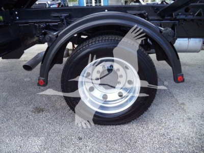 Wheel assembly showing tire and spare wheel with fender arches and suspension components of a Ford F-550 roll-off truck.
