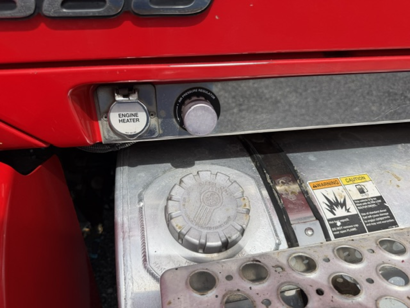 Kenworth T880 engine bay area showing engine heater control and circular access cap with warning labels on metal surface