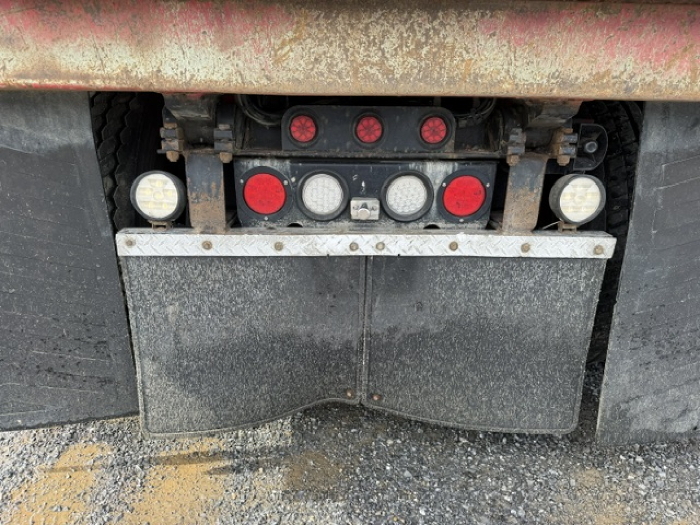 Kenworth T880 rear showing dump truck trailer connection lights and mud flaps with reflective circular lights.