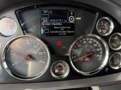 Dashboard of a Kenworth truck showing multiple gauges, digital display, and warning icons. Text on screen includes 'Screen Visibility: Hold BACK Button to Turn Off' and '448,479.1 MI' plus various gauge markings.