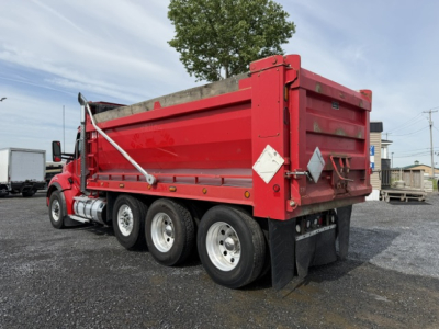 Kenworth T880 dump truck side/rear view showing red dump body and dual rear wheels.
