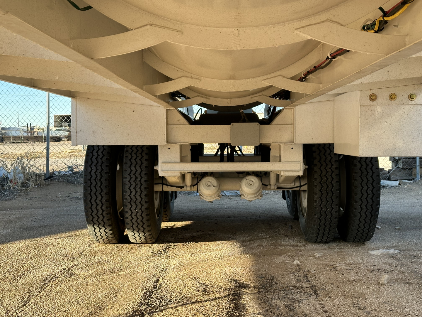 Front underside view of a Dragon 130BBL trailer showing dual rear axles, suspension, and tank chassis; no visible text other than vehicle components.