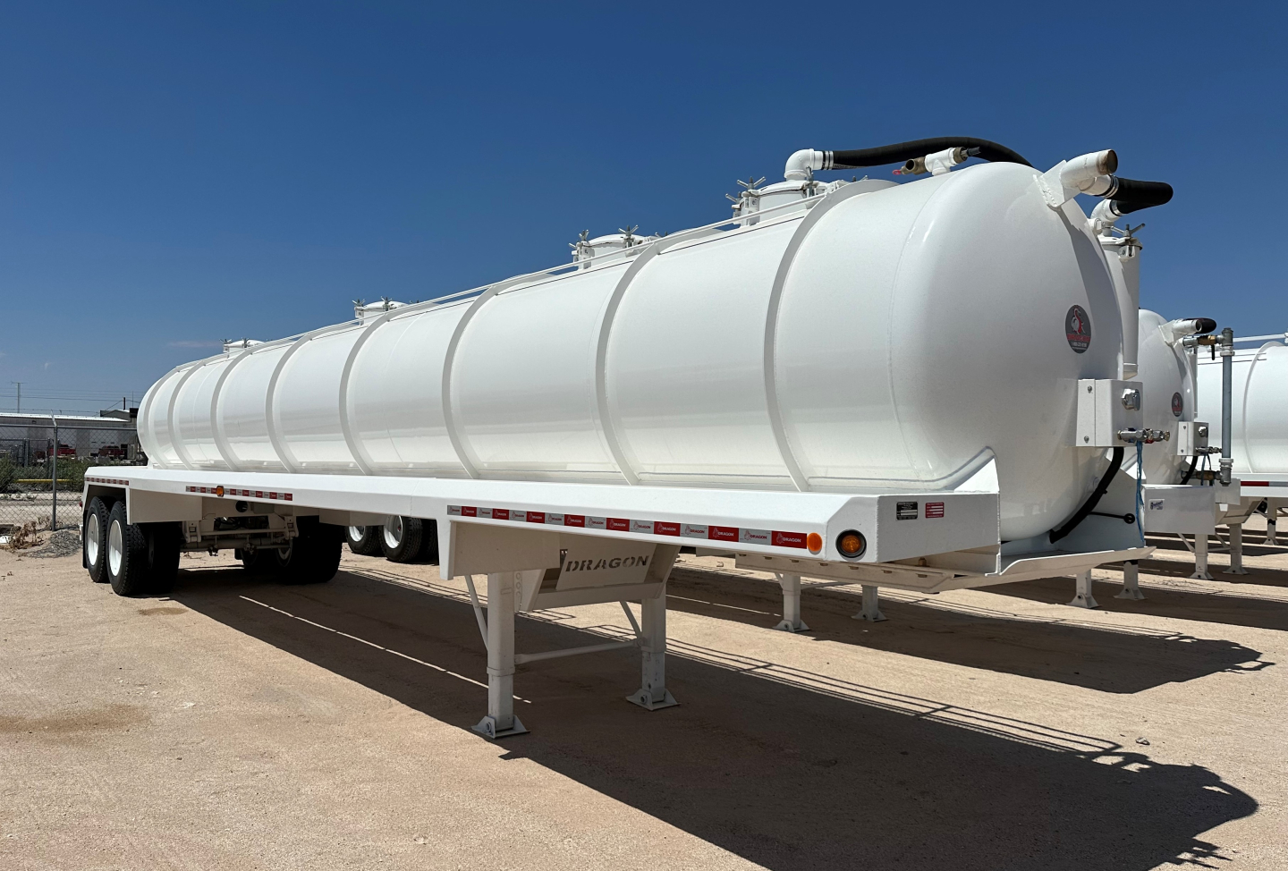 Dragon 130BBL vacuum trailer in service bay showing cylindrical white tank on a dual-axle trailer with support legs and rear hazard lights.
