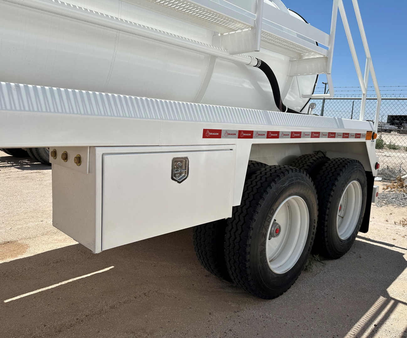 Rear side of new Dragon 130BBL vacuum trailer showing dual rear axles and aluminum tool/storage box.