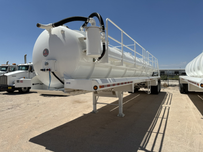 Vacuum trailer with a cylindrical white tank on a chassis, ladder/railings on top, hoses connected to a circular hatch at the front; a gauge near the rear, and a support leg visible under the front.