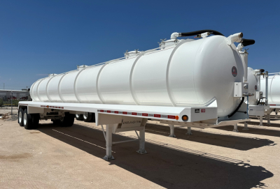 Dragon 130BBL vacuum trailer in service bay showing cylindrical white tank on a dual-axle trailer with support legs and rear hazard lights.