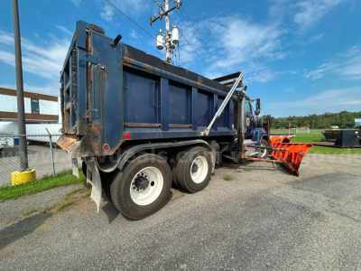 Western Star 4700 dump truck with plow attachment in service bay showing rugged metal bed and dual rear axles.