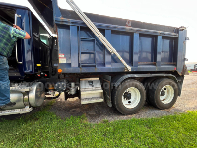 Wester Star 4700 dump truck side view showing dual rear axles and blue dump bed with metal steps and fuel tank.