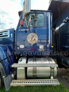 Truck cab rear showing steps and fuel tanks, blue Western Star 4700 with emblem, side mirrors, and window, plow category used vehicle.