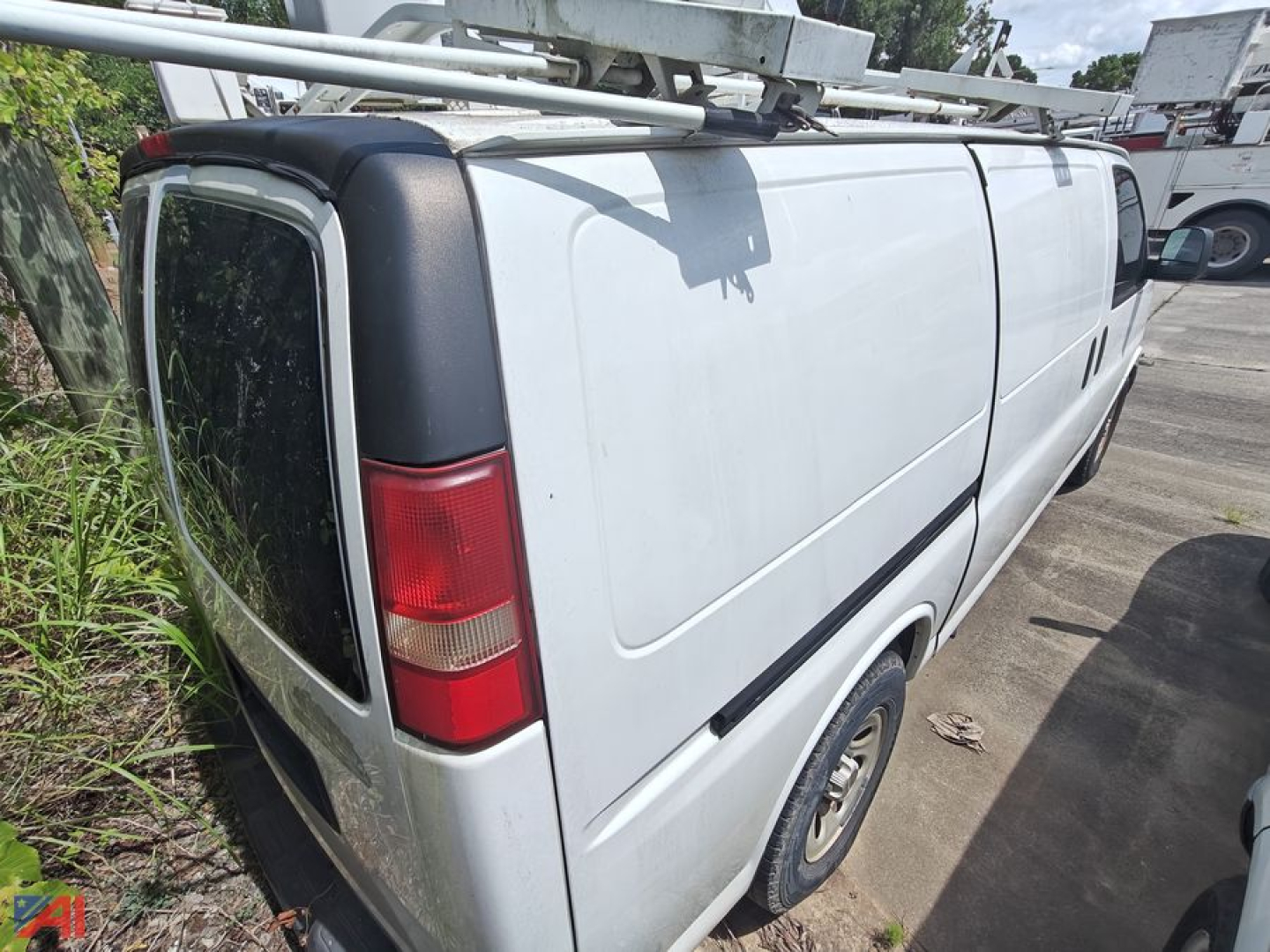 Commercial cargo van side and rear view showing white 2009 Chevrolet Express 1500 cargo van with ladder rack, single rear door, and black corner guards.