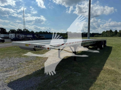 Flatbed trailer showing long aluminum deck and tandem axles with support legs, 2025 Reitnouer Maxmiser branding, parked on grass.