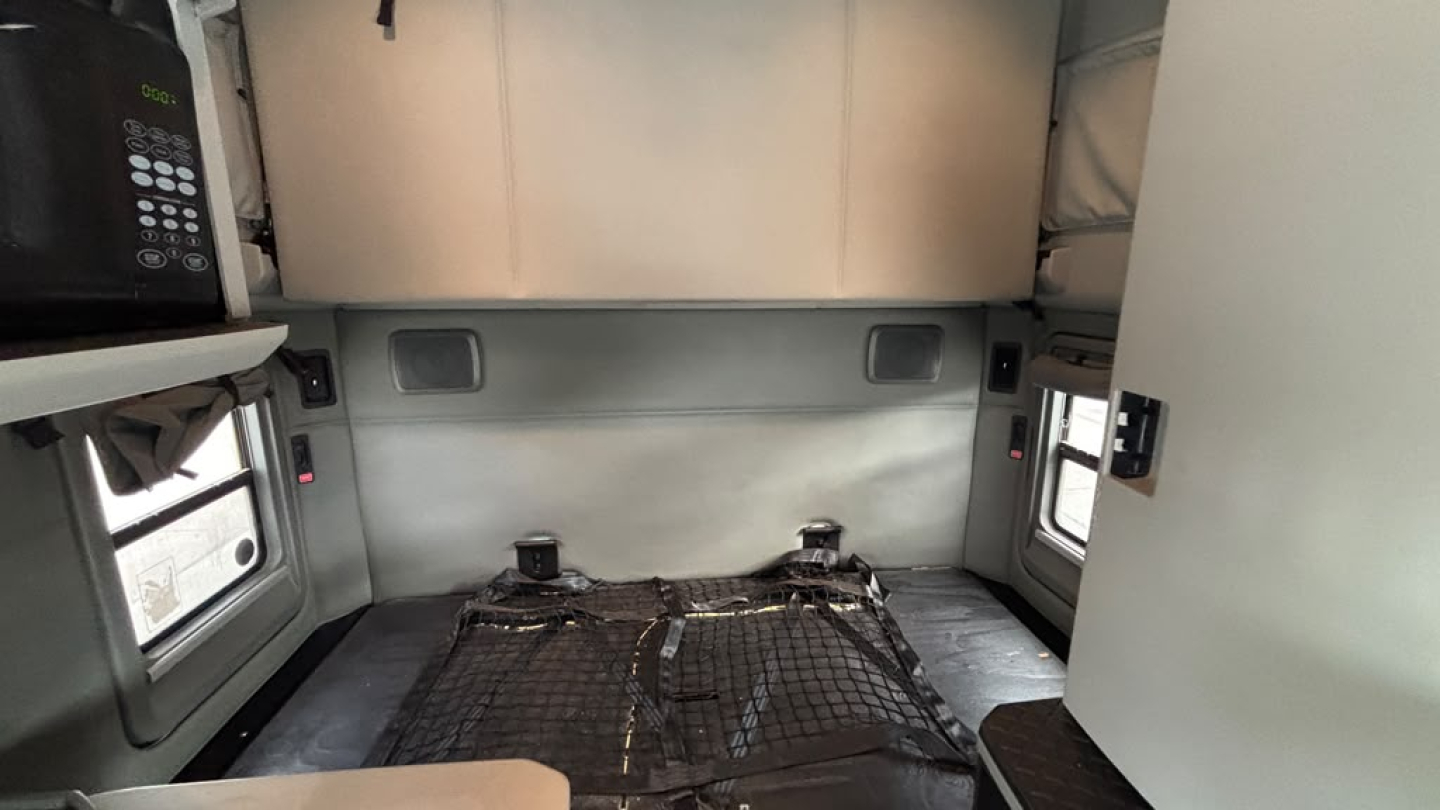 Kenworth T680 sleeper cab interior showing rear area with mattress base frame and side windows.