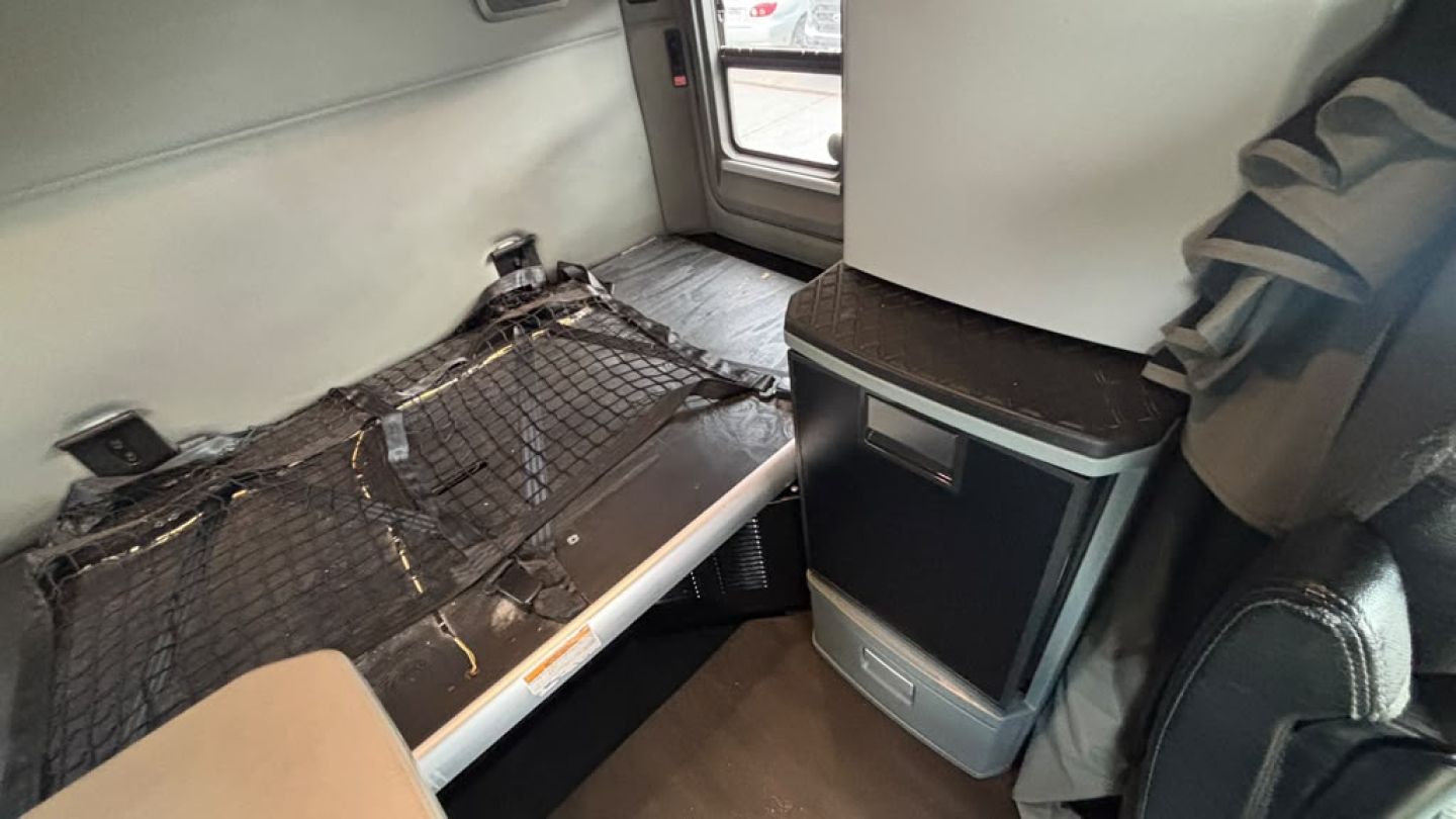 Kenworth T680 interior sleeper area with cargo area showing storage shelf and netting.