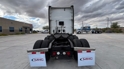 Kenworth T680 truck chassis rear view showing fifth wheel, dual rear axles, mud flaps with MHC logo, and utility panels.
