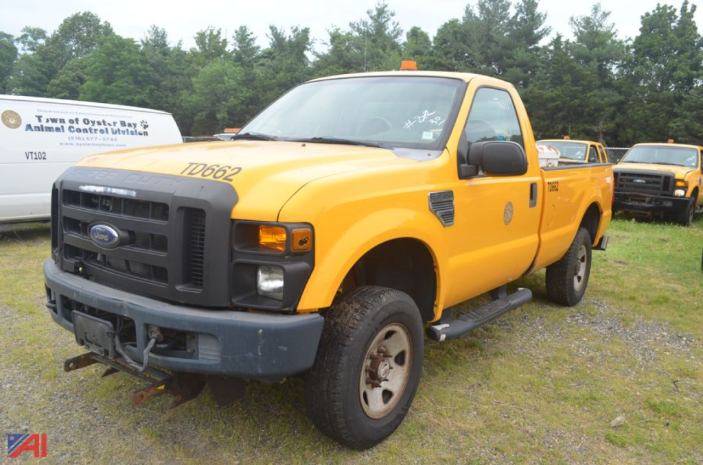 Ford F-250 Super Duty dump truck showing front grille, yellow body, black bumper, and side step; VIN/marker numbers on hood.