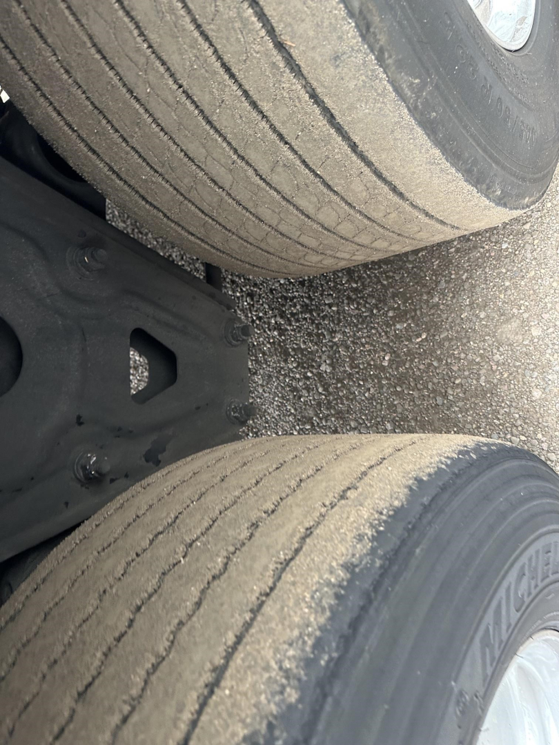 Rear view of a 2020 Utility 3000R trailer axle with dual tires and sand/dust on tread surfaces; visible wheel rims and leaf spring area.