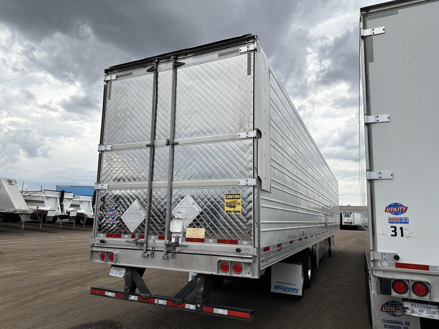 Rear view of a used 2020 Utility 3000R trailer with diamond plate aluminum doors, dual rear doors, and taillights. Visible stickers and warning labels on doors, bumper with lights.