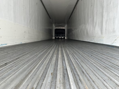 Trailer interior showing ribbed floor and side walls of a refrigerated trailer with rear doorway in view.