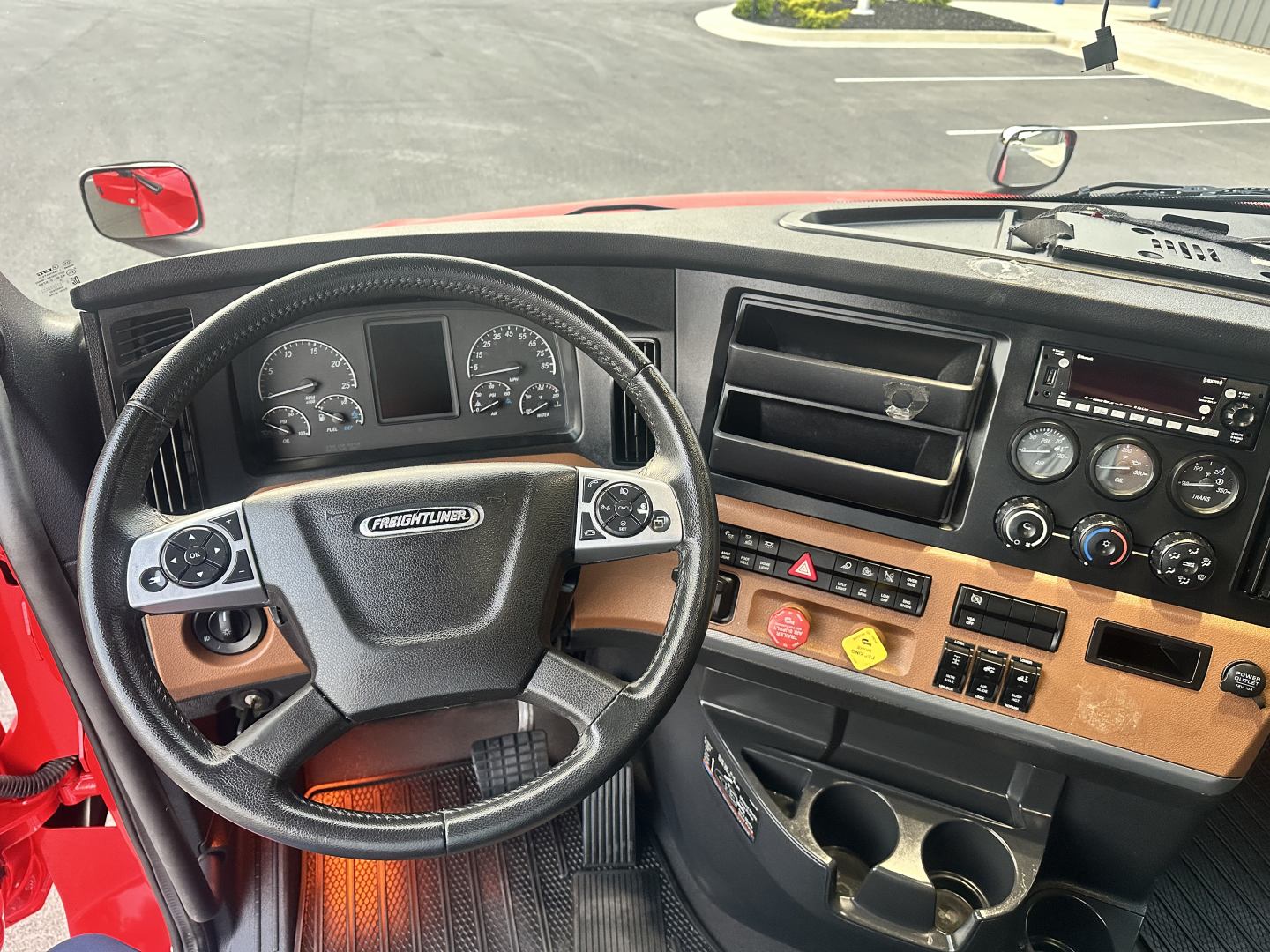 Cab interior of a Freightliner Cascadia 126 with steering wheel, dashboard controls, and instrument cluster visible.