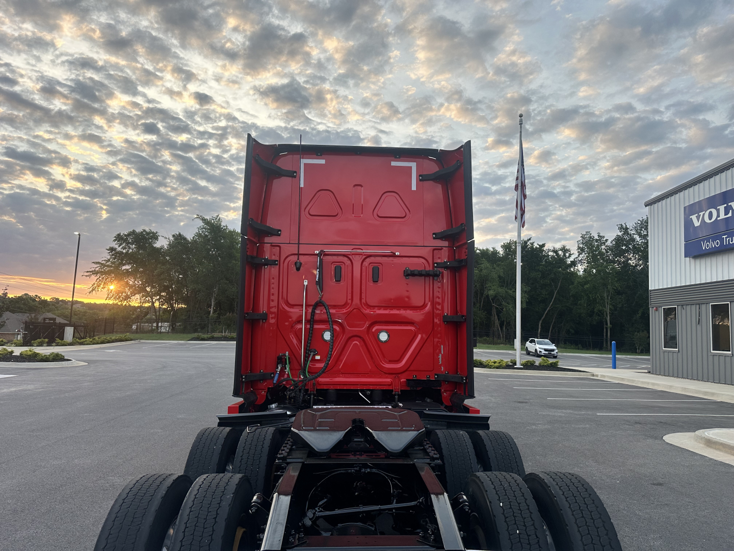 Freightliner Cascadia 126 truck cab rear view showing red exterior, back of sleeper area, chassis and dual rear axles.