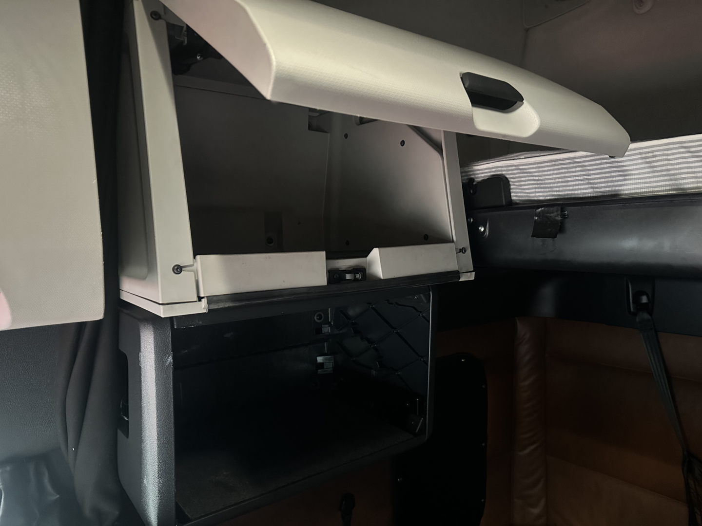 Cabin interior view of a Freightliner Cascadia 126 showing an open storage drawer and dashboard area in a sleeper cab.