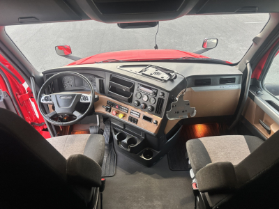 Dashboard and driver’s cockpit of a Freightliner Cascadia 126 interior with steering wheel, center console, and dashboard controls.