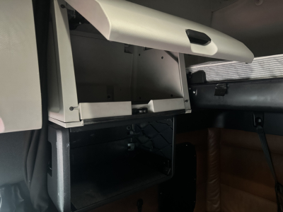 Cabin interior view of a Freightliner Cascadia 126 showing an open storage drawer and dashboard area in a sleeper cab.