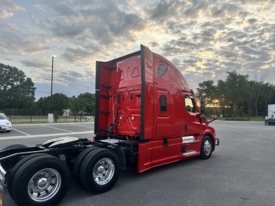 Freightliner Cascadia 126 sleeper tractor rear-three-quarter view showing red exterior and dual rear axles.