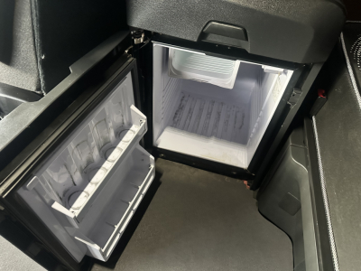 Freightliner Cascadia 126 cab interior showing open small fridge/freezer with shelves and a compact fridge in the cab, compact freezer unit and interior storage.