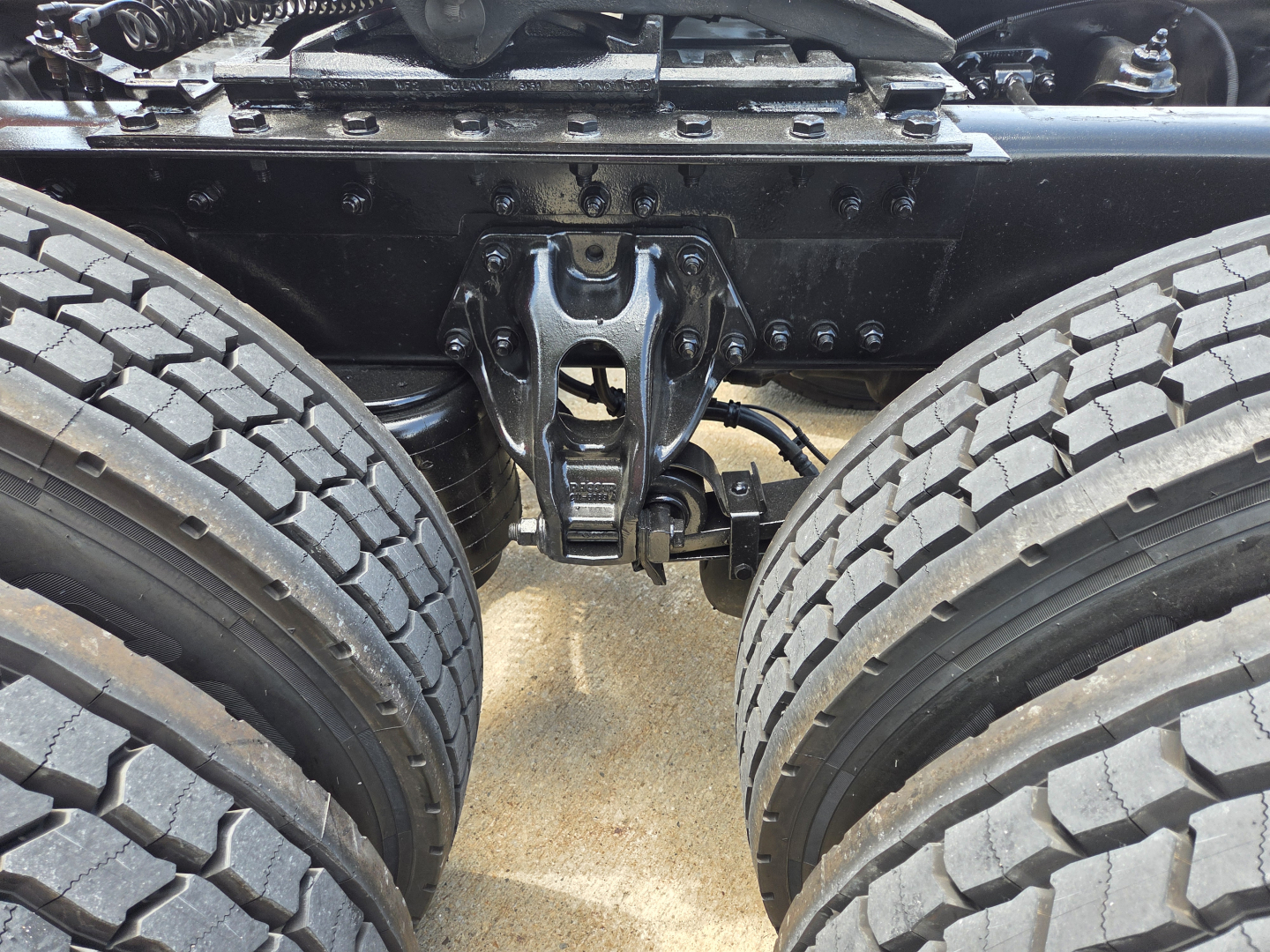 Kenworth truck chassis with dual rear axles and fifth wheel hitch showing undercarriage and suspension components.