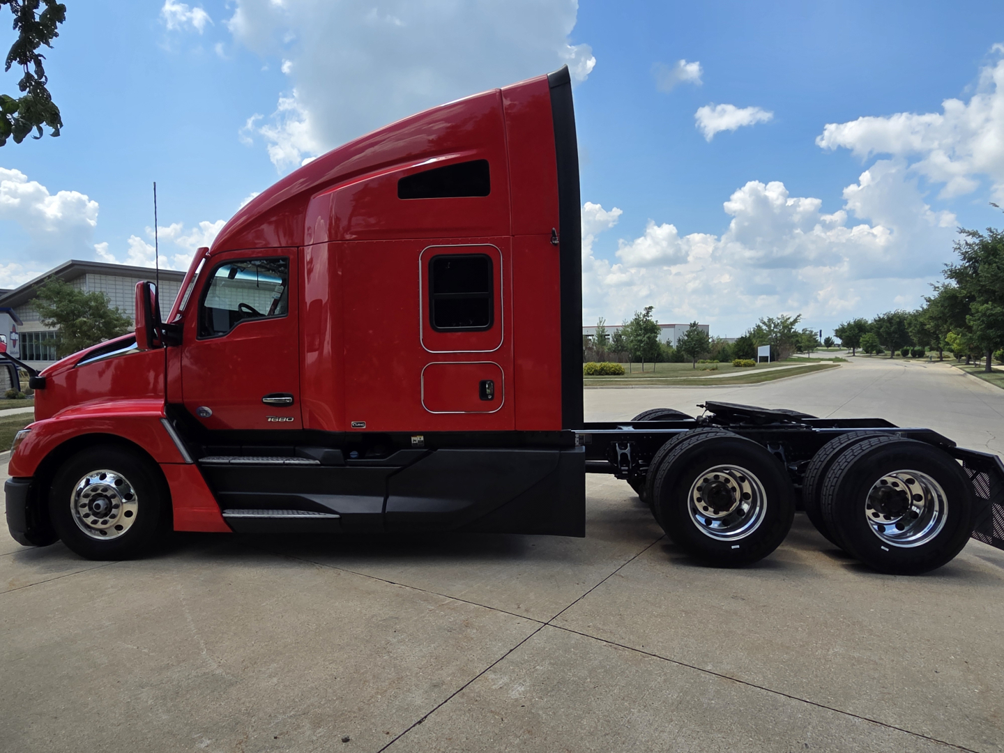 Kenworth T680 sleeper cab tractor in red side view showing rear wheels and aerodynamic body lines.