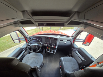 Interior of a 2024 Kenworth T680 cab showing driver seat, steering wheel, dashboard, center console, and passenger seat in view