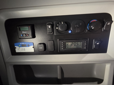 Kenworth T680 dash panel showing controls, vents, and digital readout in a sleeper cab. Includes climate knobs, radio, and accessory switches.