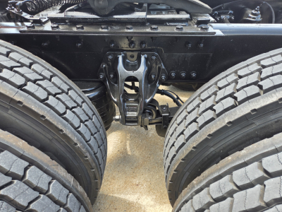 Kenworth truck chassis with dual rear axles and fifth wheel hitch showing undercarriage and suspension components.