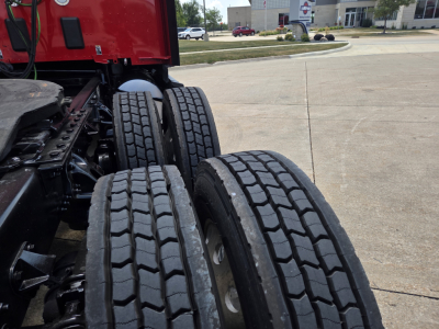 Kenworth T680 wheel dual rear axle tires view showing multiple tire treads and red truck cab in background.
