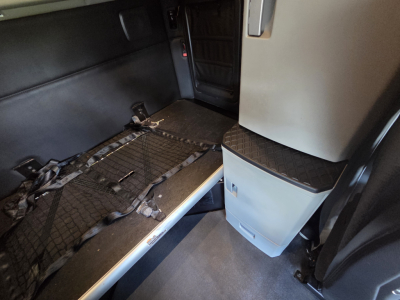 Kenworth T680 sleeper cab interior showing bed area with cargo net and storage drawers.